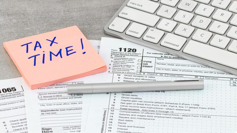 Tax time sticky note reminder placed above tax forms